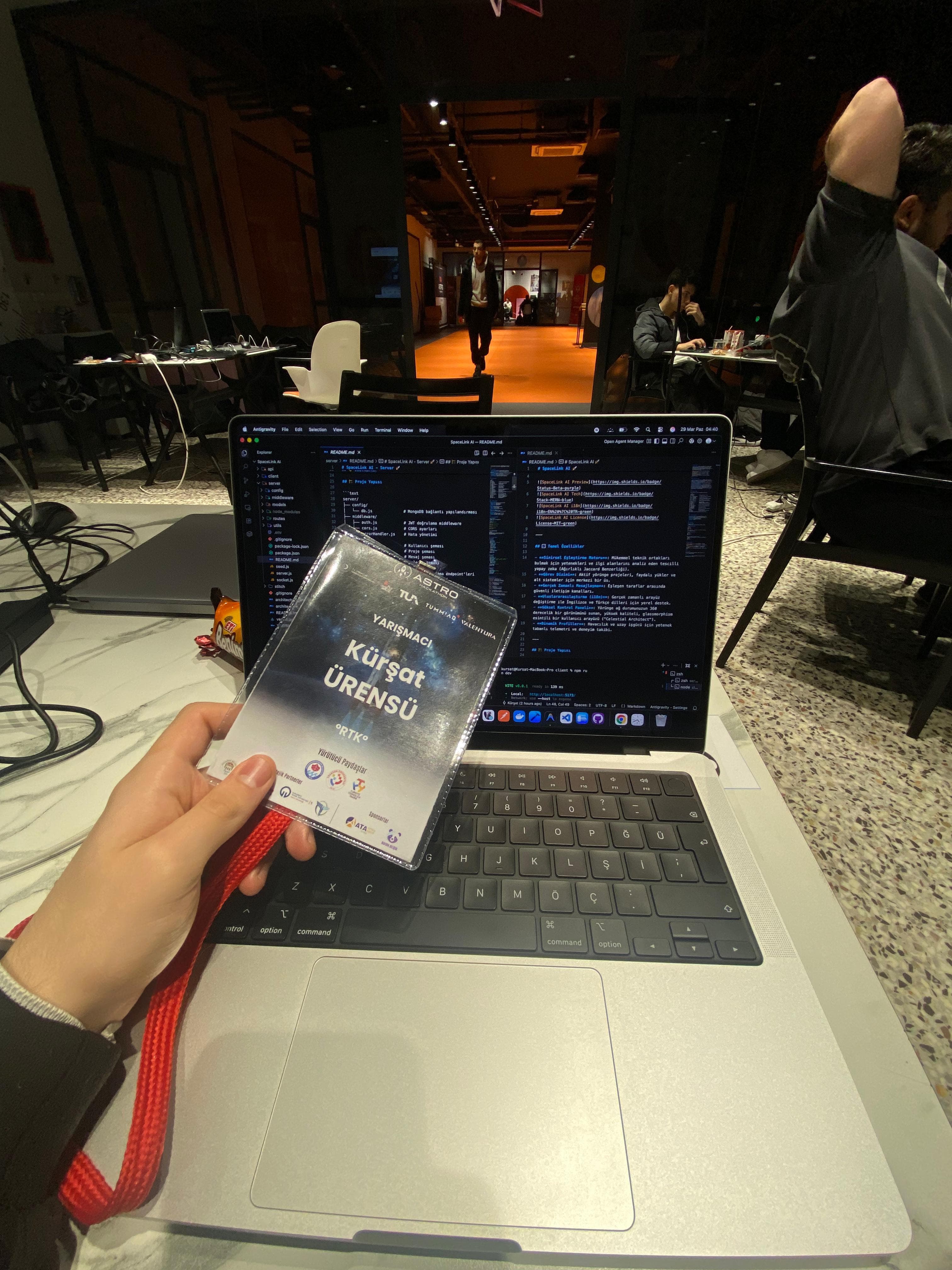 Astro Hackathon yarışmacı yaka kartı ve arkada kod yazılan dizüstü bilgisayar