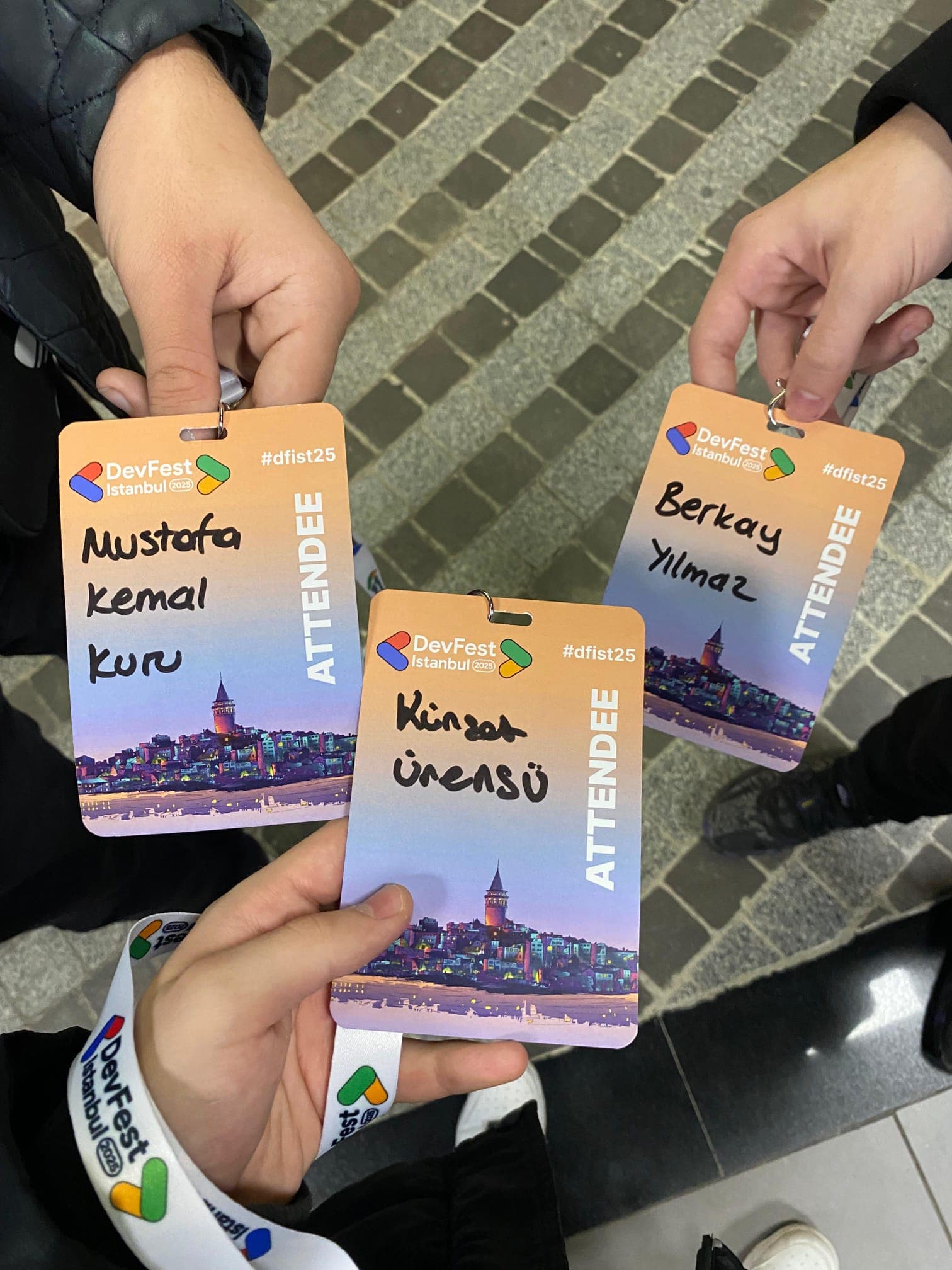 GDG DevFest İstanbul 2025'e ait üç katılımcı yaka kartı; ortadaki Kürşat Ürensü adına
