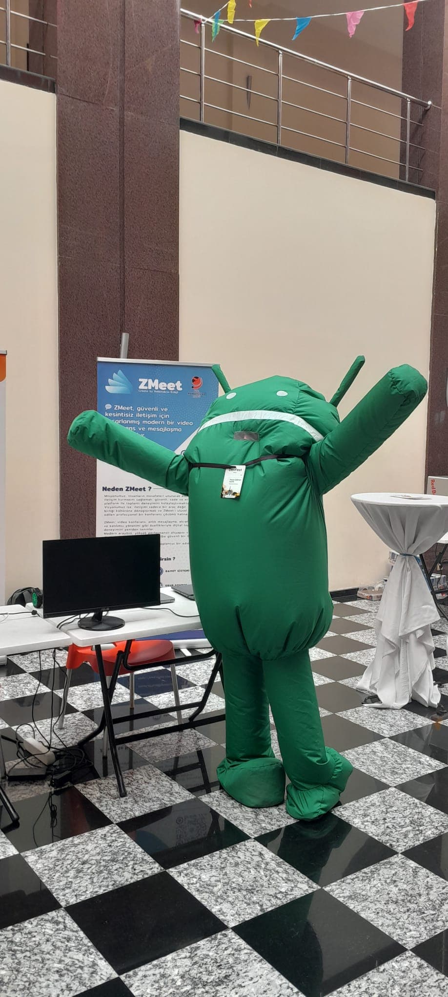 GDG DevFest Trabzon 2025'te ZMeet standının önünde şişme Android maskot kostümü